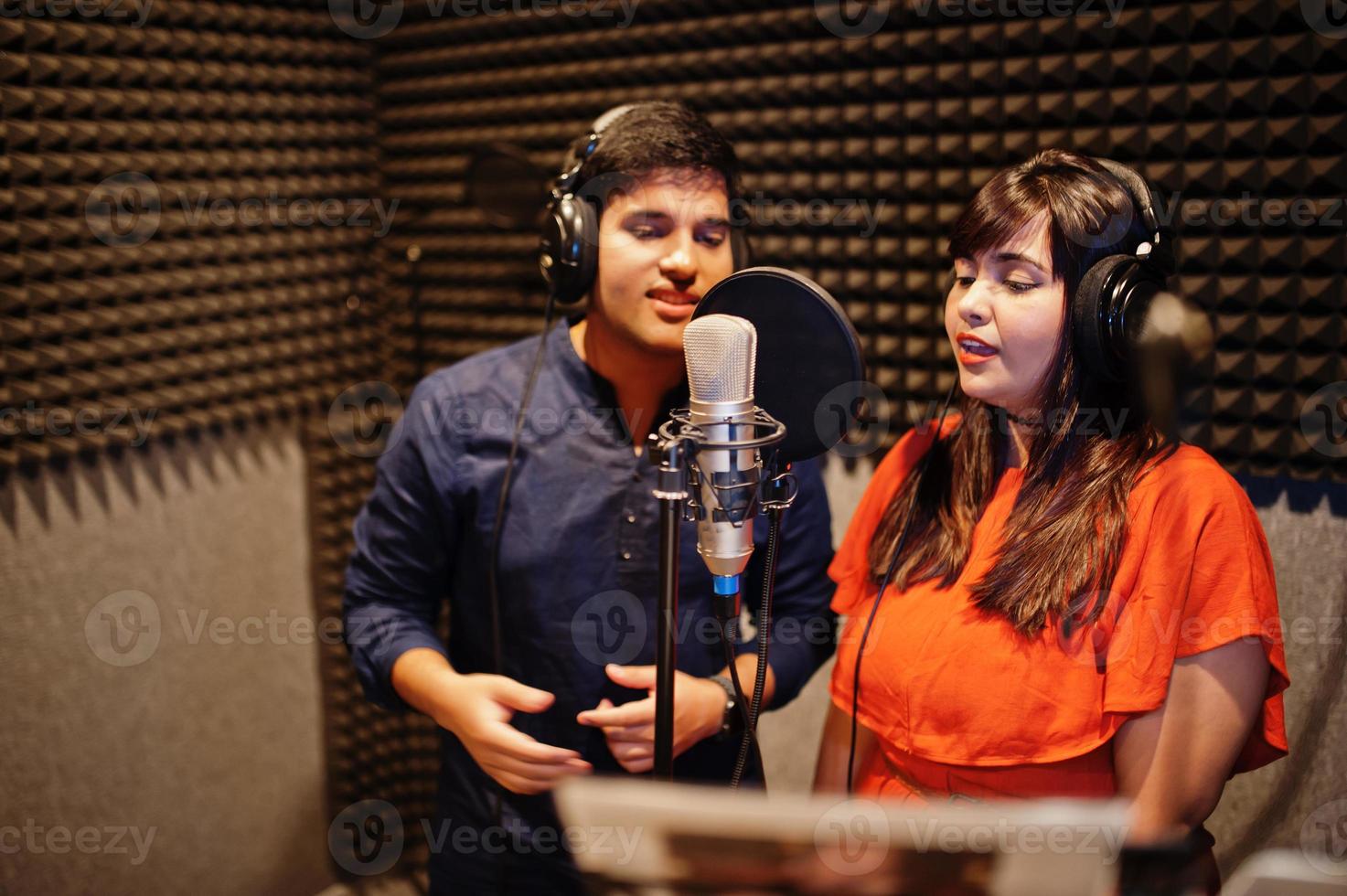 Young asian duet singers with microphone recording song in record music studio. photo