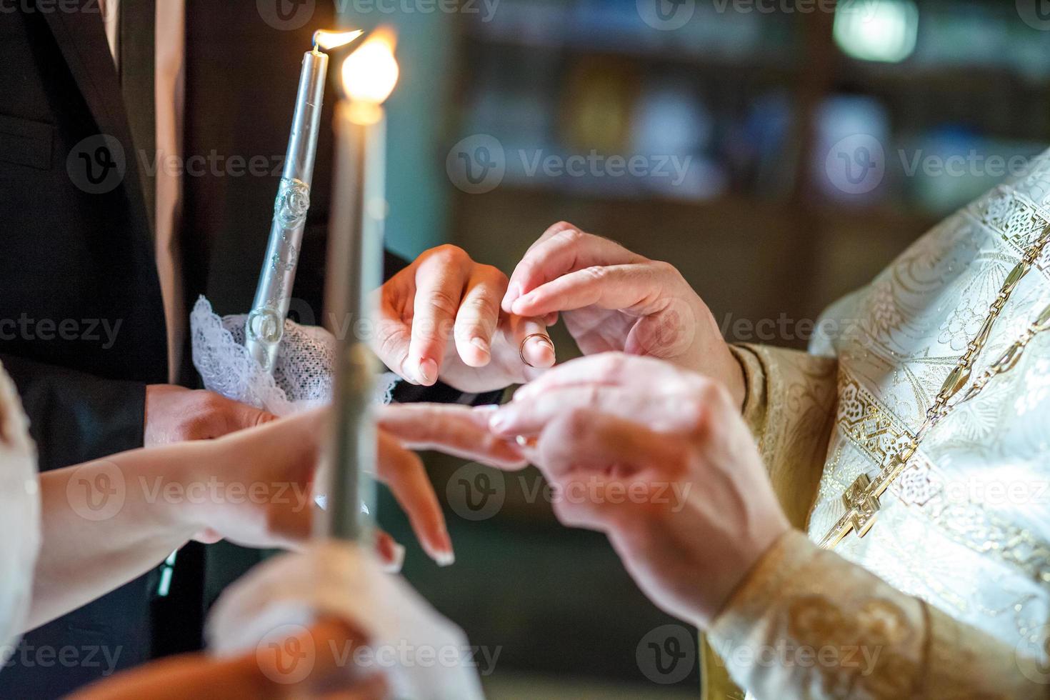 el sacerdote ayuda a los recién casados a intercambiar anillos en la ceremonia de boda en la iglesia foto