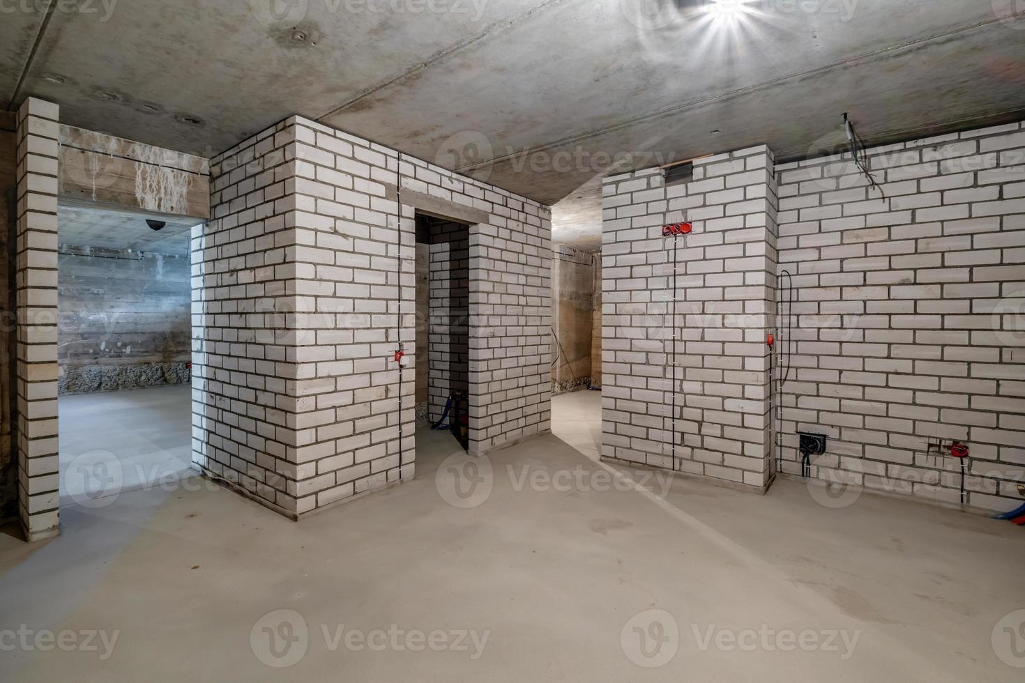 Empty basement room with minimal preparatory repairs in interior with white brick walls photo