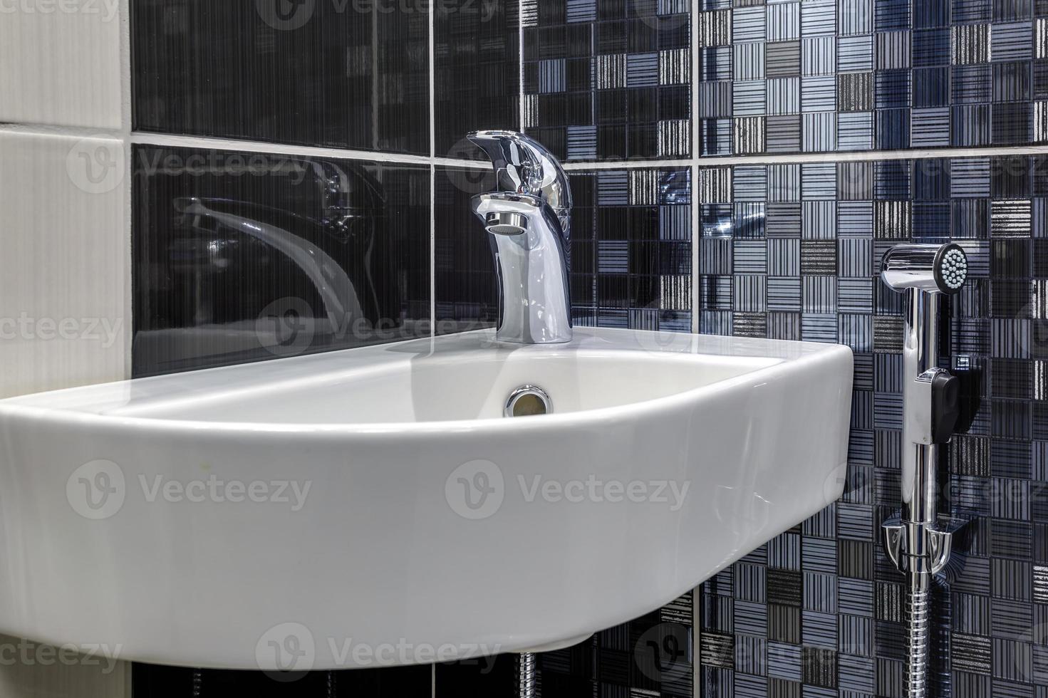 water tap sink with faucet in expensive loft bathroom. detail of a corner shower cabin with wall mount shower attachment photo
