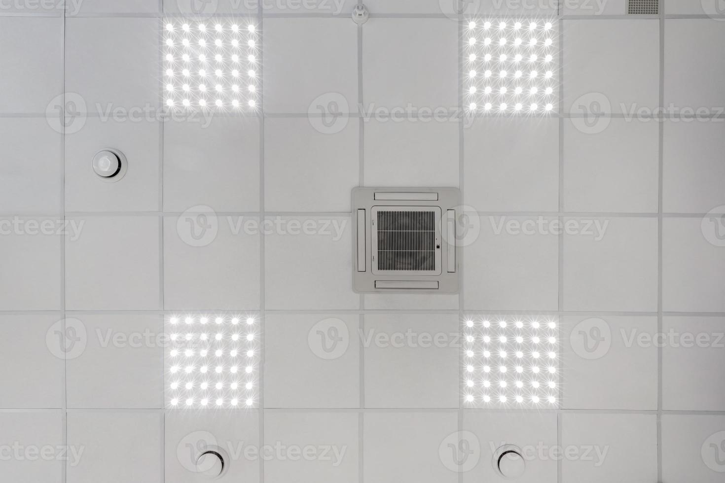 cassette suspended ceiling with square halogen spots lamps and drywall construction in empty room in apartment or house. Stretch ceiling white and complex shape. Looking up view photo