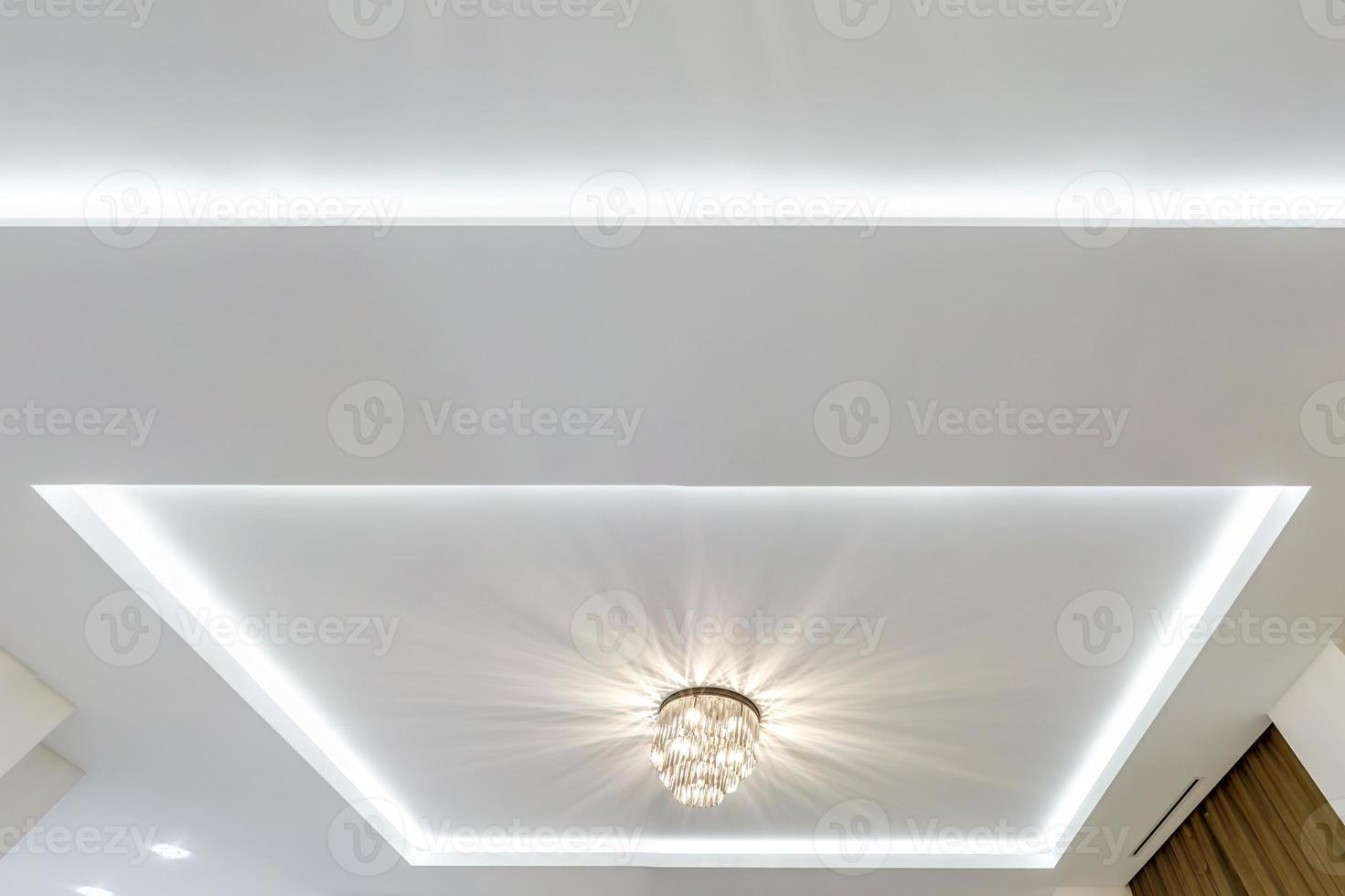 looking up on suspended ceiling with halogen spots lamps and drywall construction in empty room in apartment or house. Stretch ceiling white and complex shape. photo