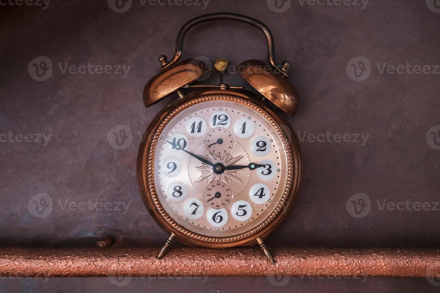 vintage old copper alarm clock on dark background photo