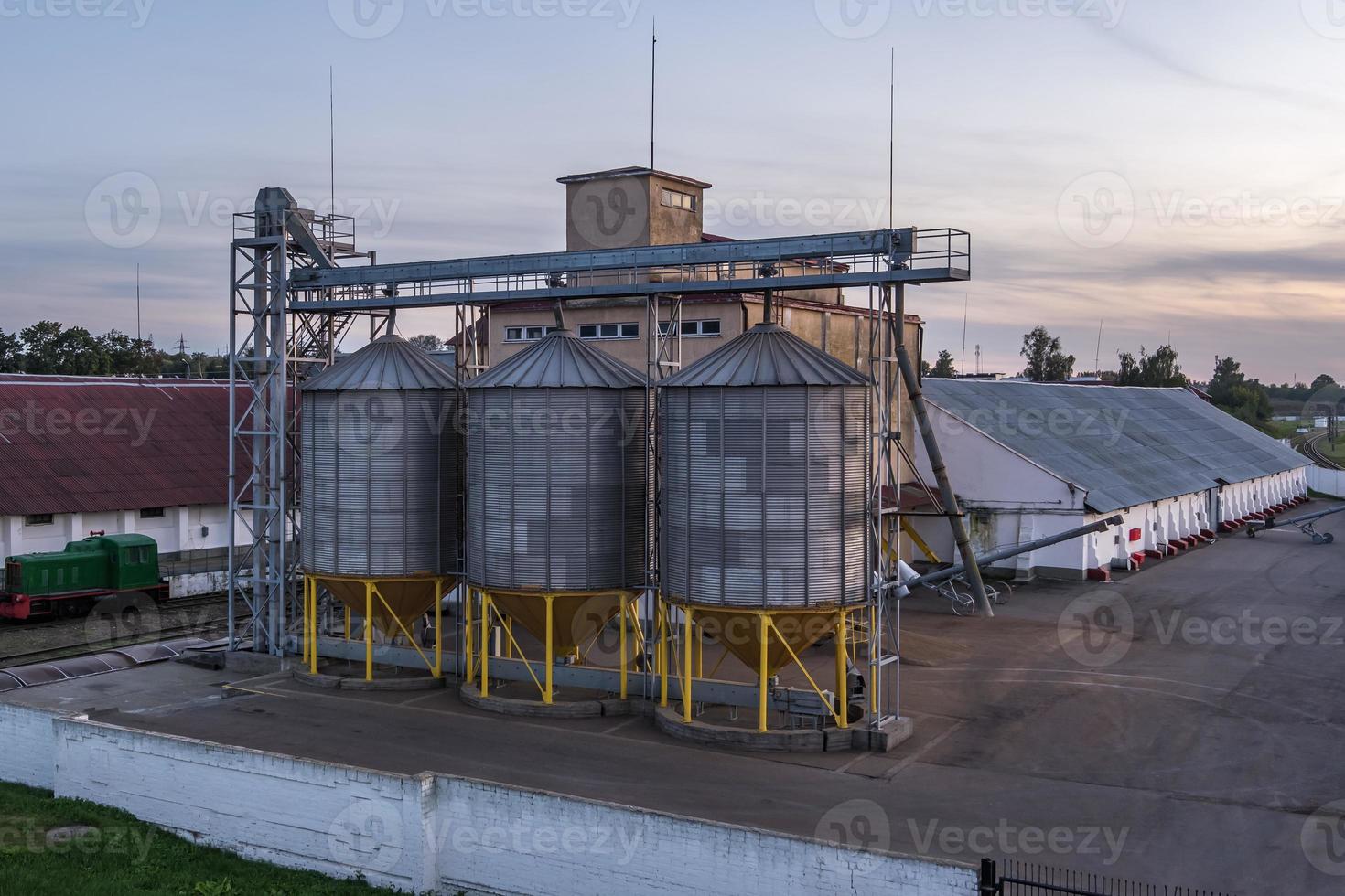 Modern Granary elevator with silver silos on agro-processing and manufacturing plant for processing drying cleaning and storage of agricultural products, flour, cereals and grain. photo