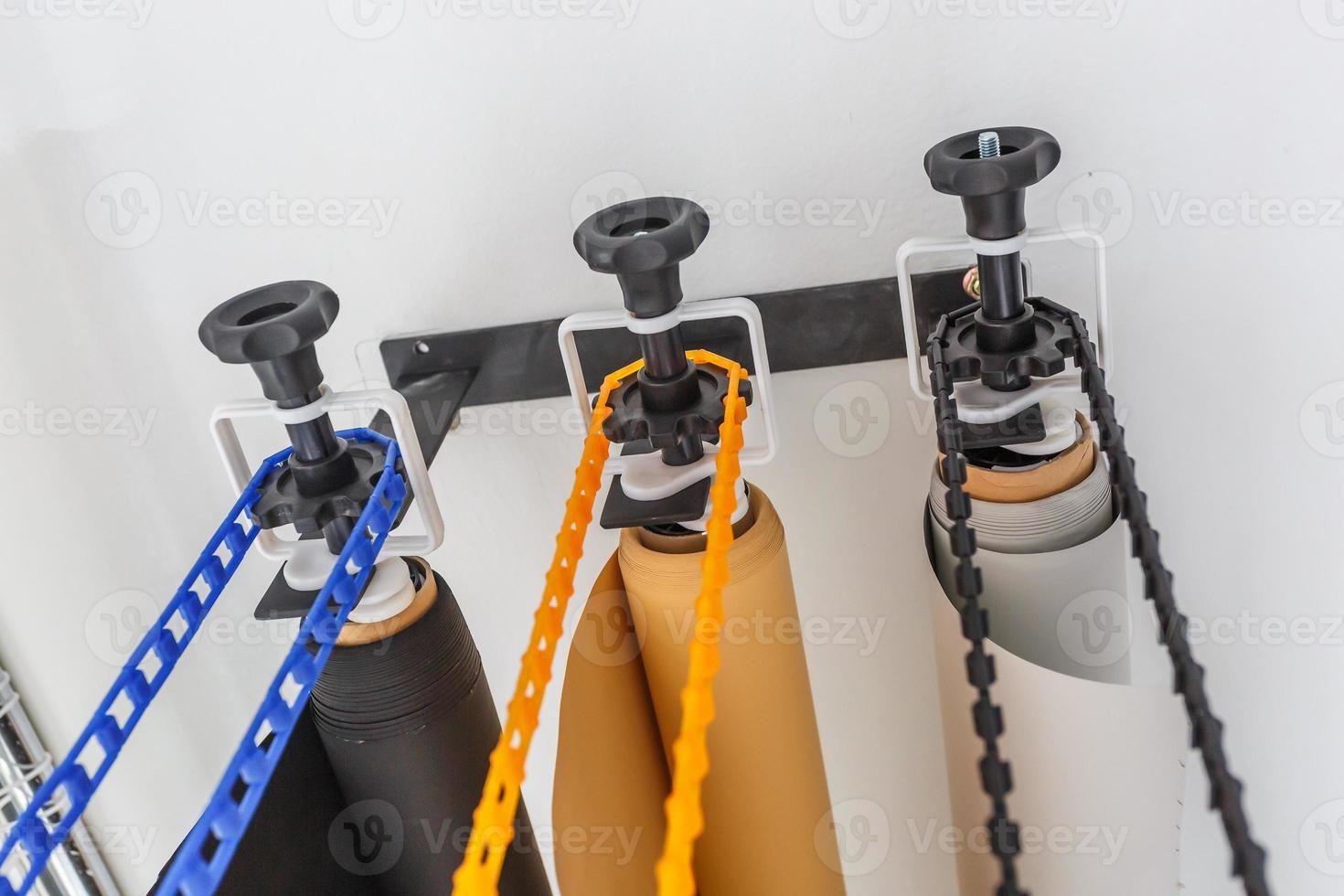 mounting manual support system for photo backdrops in modern studio. Rolls of colorful paper backgrounds for photo studio hang on the wall