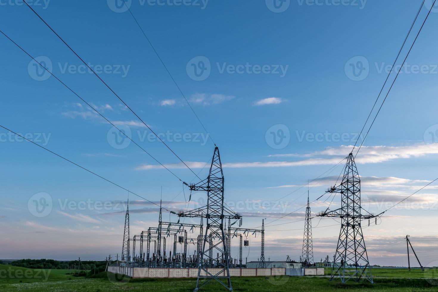Silhouette of the high voltage electric pylon towers on the background of beautiful evening clouds photo