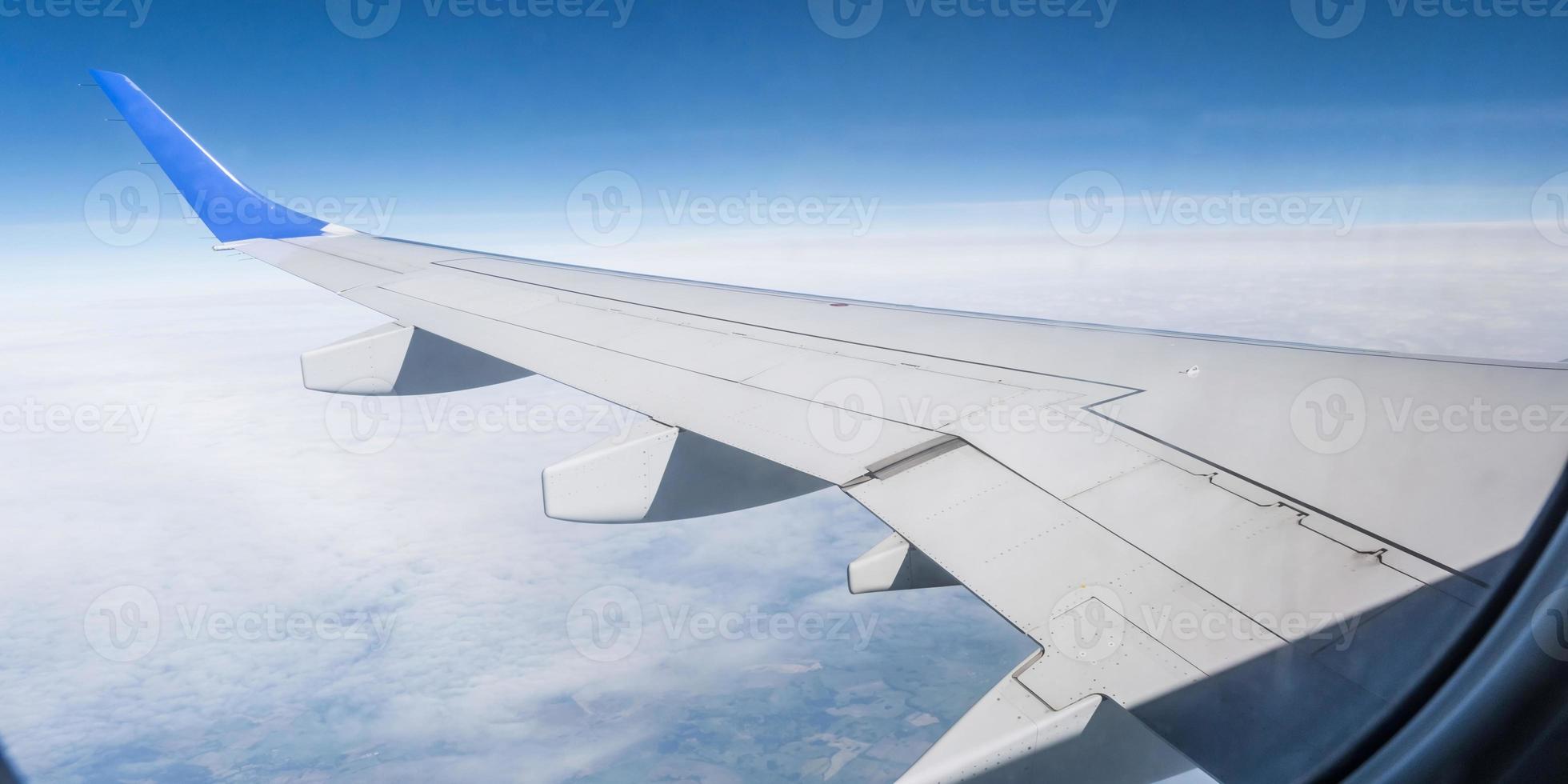 aircraft wing from the aircraft window overlooking the blue sky and beautiful clouds photo