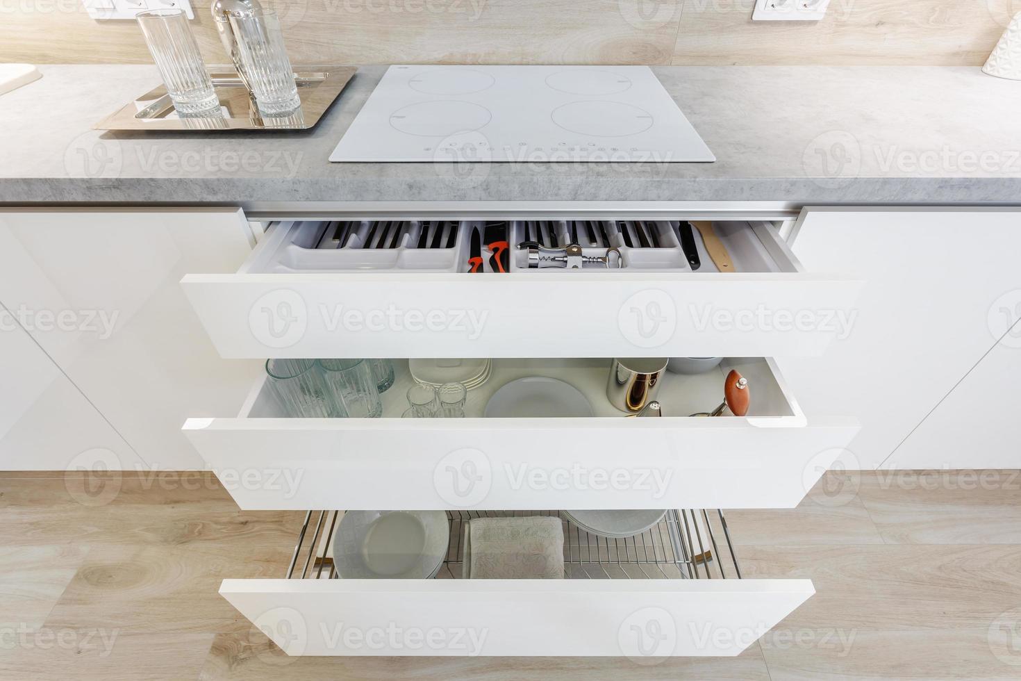 set of plates, cups, knives, forks and wine glasses on the shelf in the kitchen cabinet photo