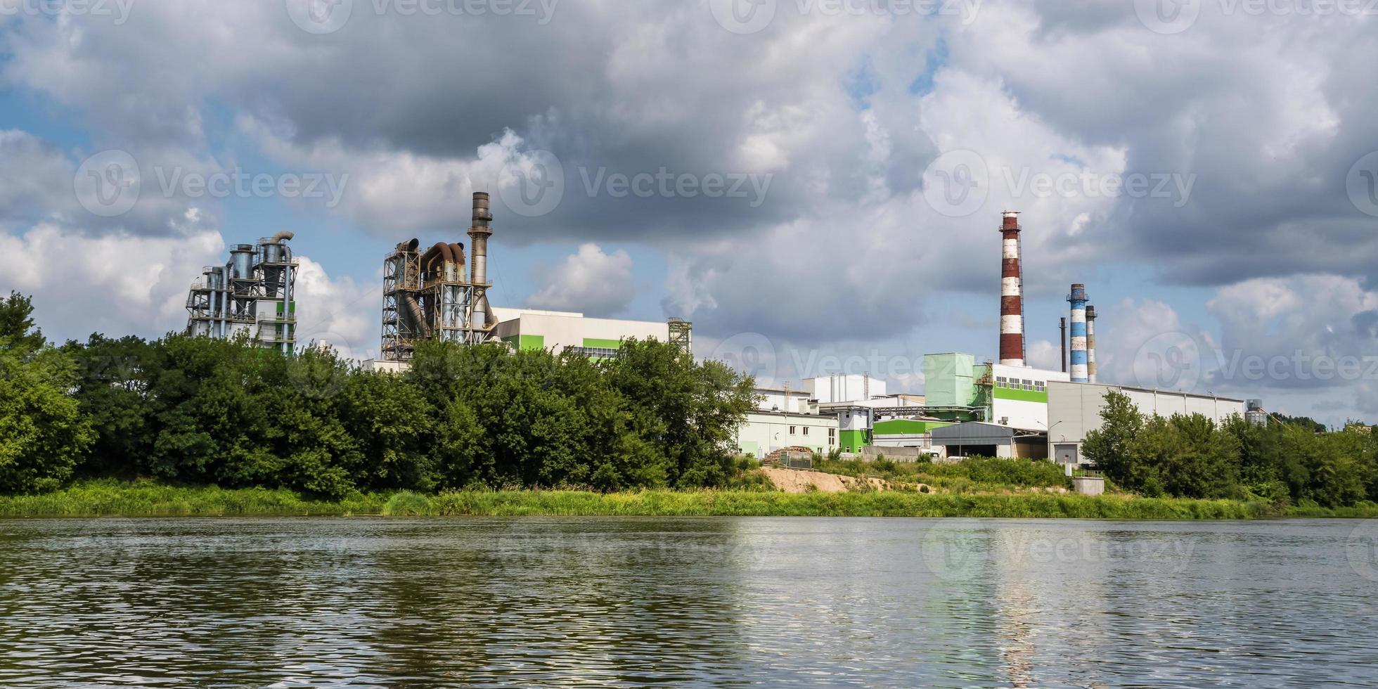 pipes of woodworking enterprise plant sawmill near river. Air pollution concept. Industrial landscape environmental pollution waste of thermal power plant photo