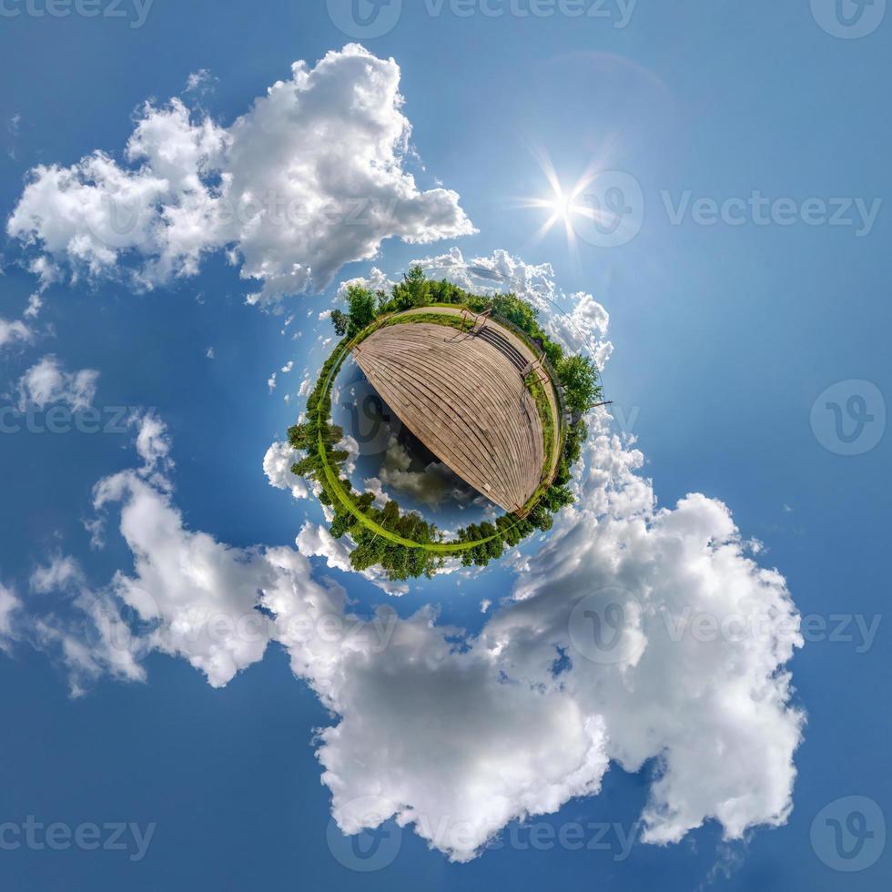 tiny planet in blue sky with beautiful clouds. Transformation of spherical panorama 360 degrees. Spherical abstract aerial view. Curvature of space. photo