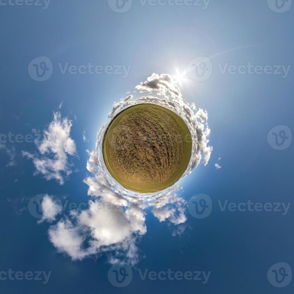 green tiny planet in blue sky with beautiful clouds. Transformation of spherical panorama 360 degrees. Spherical abstract aerial view. Curvature of space. photo