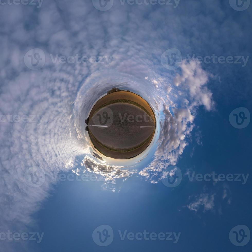 tiny planet in blue sky with beautiful clouds. Transformation of spherical panorama 360 degrees. Spherical abstract aerial view. Curvature of space. photo