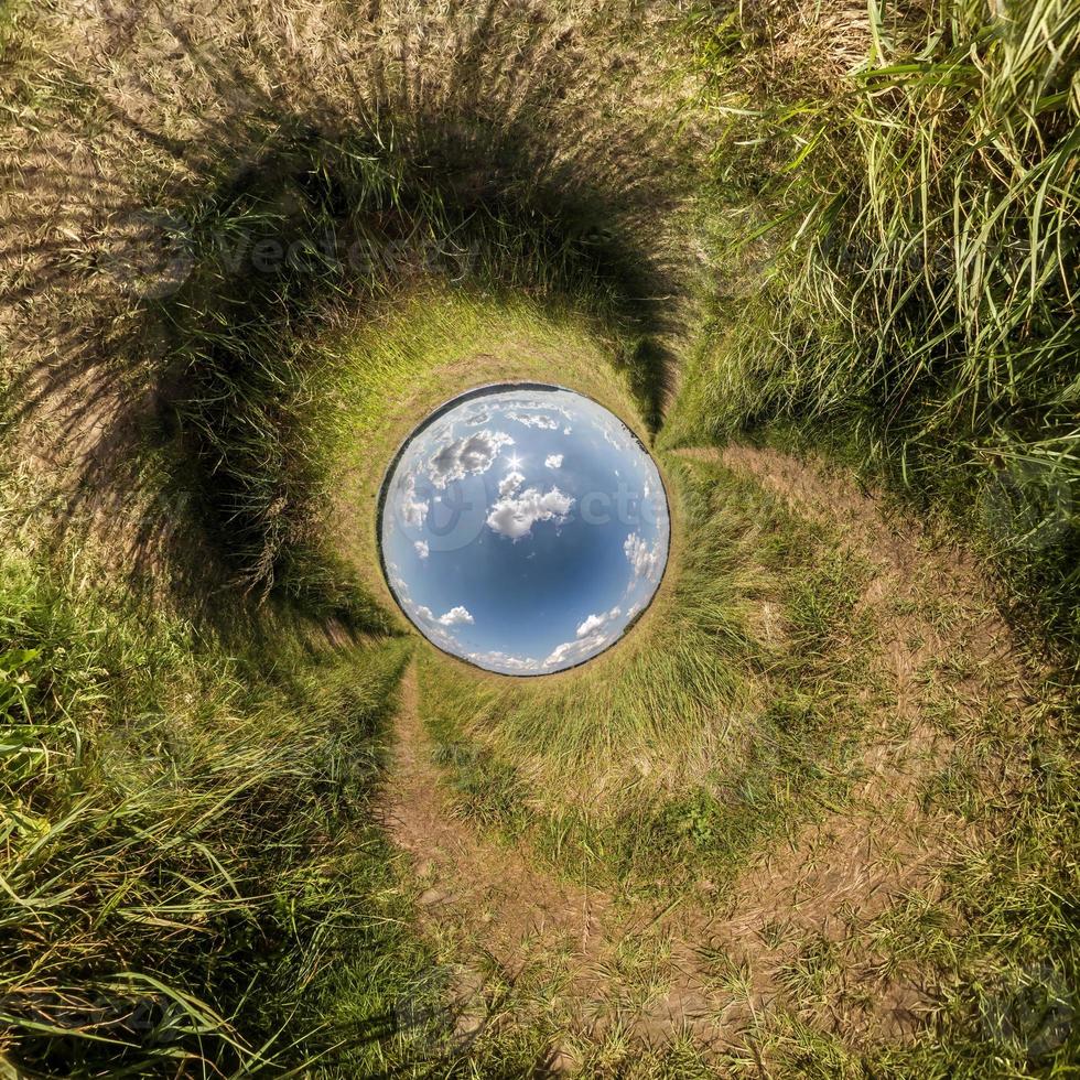 Inversion of blue little planet transformation of spherical panorama 360 degrees. Spherical abstract aerial view on field with awesome beautiful clouds. Curvature of space. photo