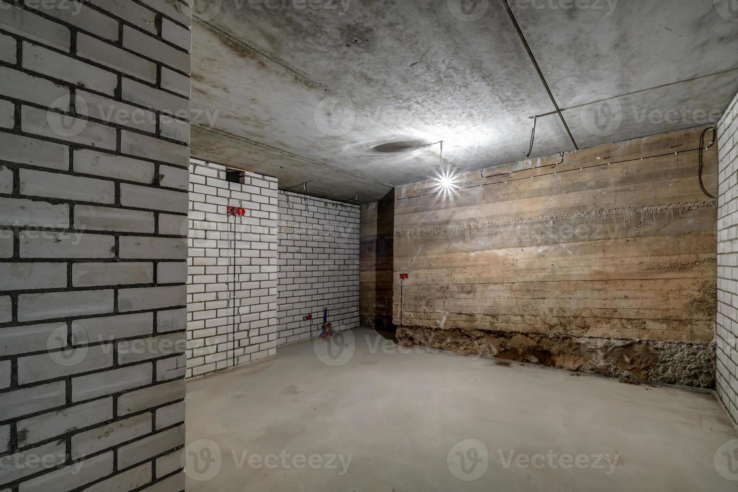 Empty unfurnished basement room with minimal preparatory repairs. interior with white brick walls photo