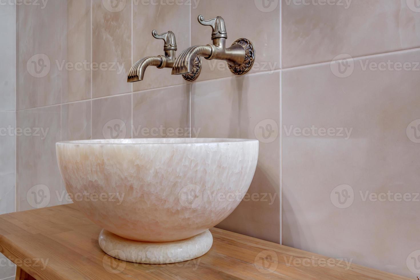 metal water tap sink with faucet in expensive bathroom. detail of a corner toilet with wall mount shower attachment photo