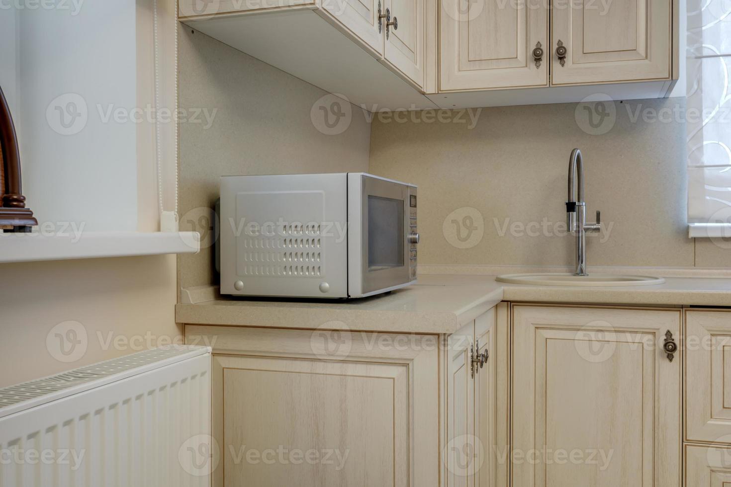 Interior of the small living equipped kitchen in studio apartments in minimalistic style with light color photo