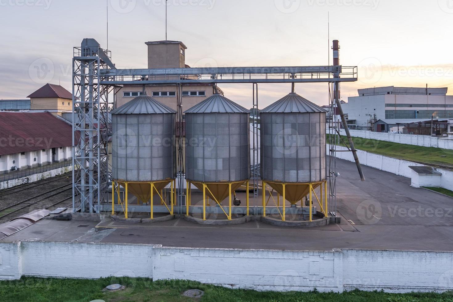 Modern Granary elevator with silver silos on agro-processing and manufacturing plant for processing drying cleaning and storage of agricultural products, flour, cereals and grain. photo