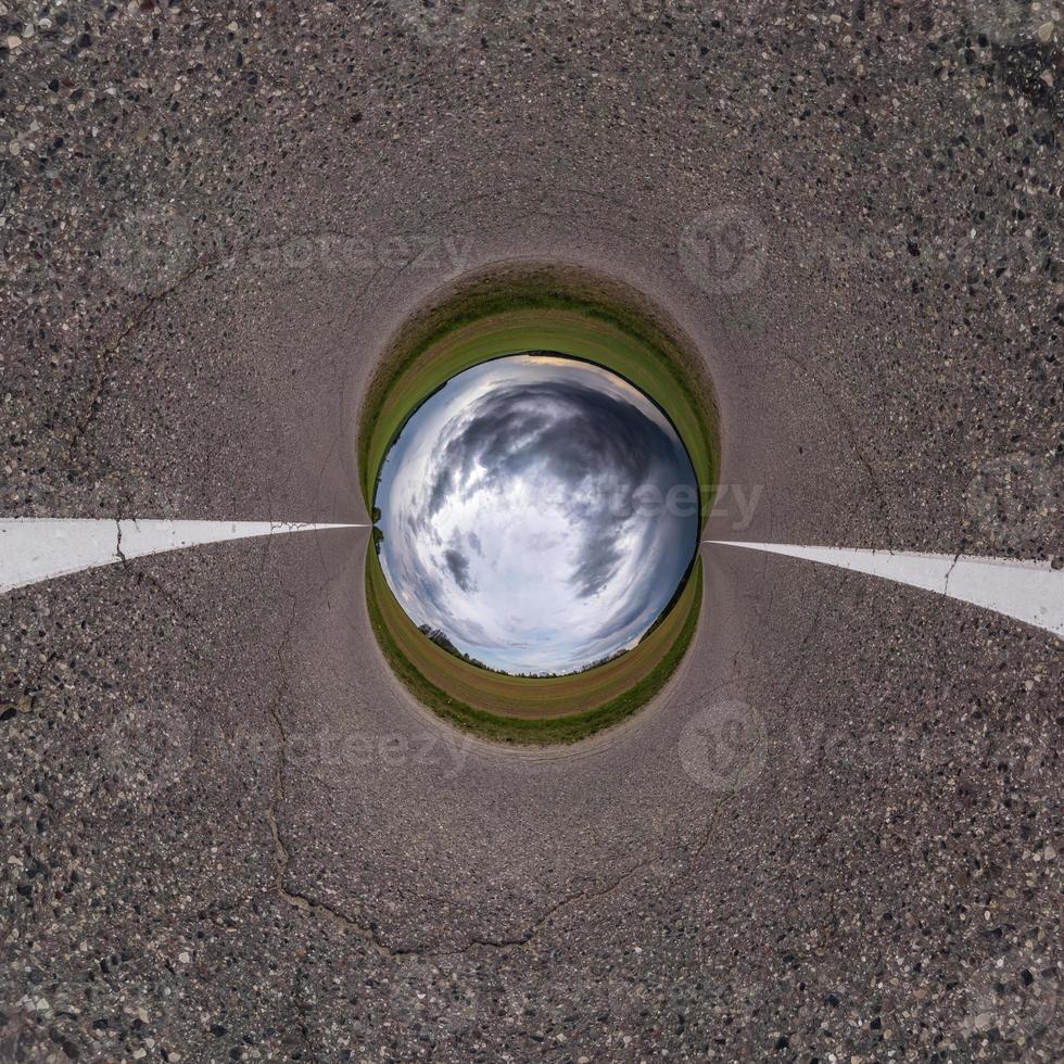 Inversion of blue little planet transformation of spherical panorama 360 degrees. Spherical abstract aerial view on road with awesome beautiful clouds. Curvature of space. photo
