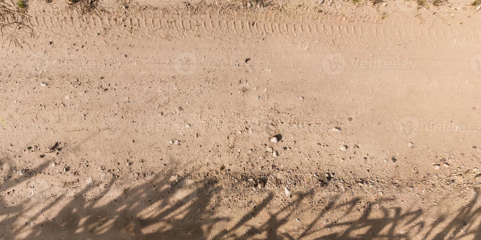 view from above on surface of gravel road with car tire tracks photo