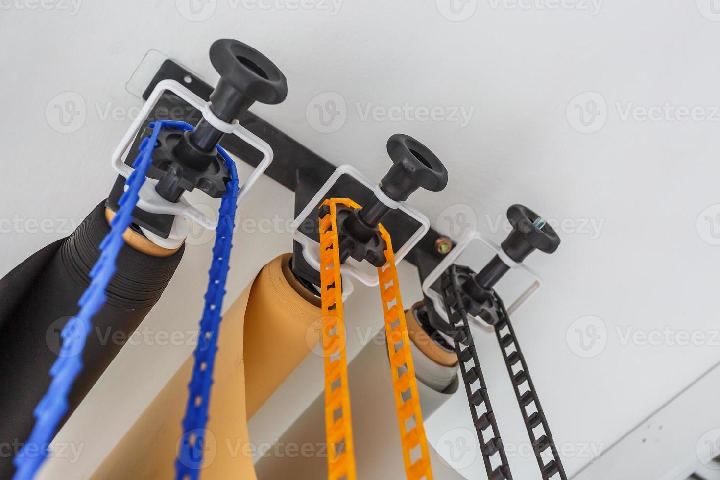 mounting manual support system for photo backdrops in modern studio. Rolls of colorful paper backgrounds for photo studio hang on the wall