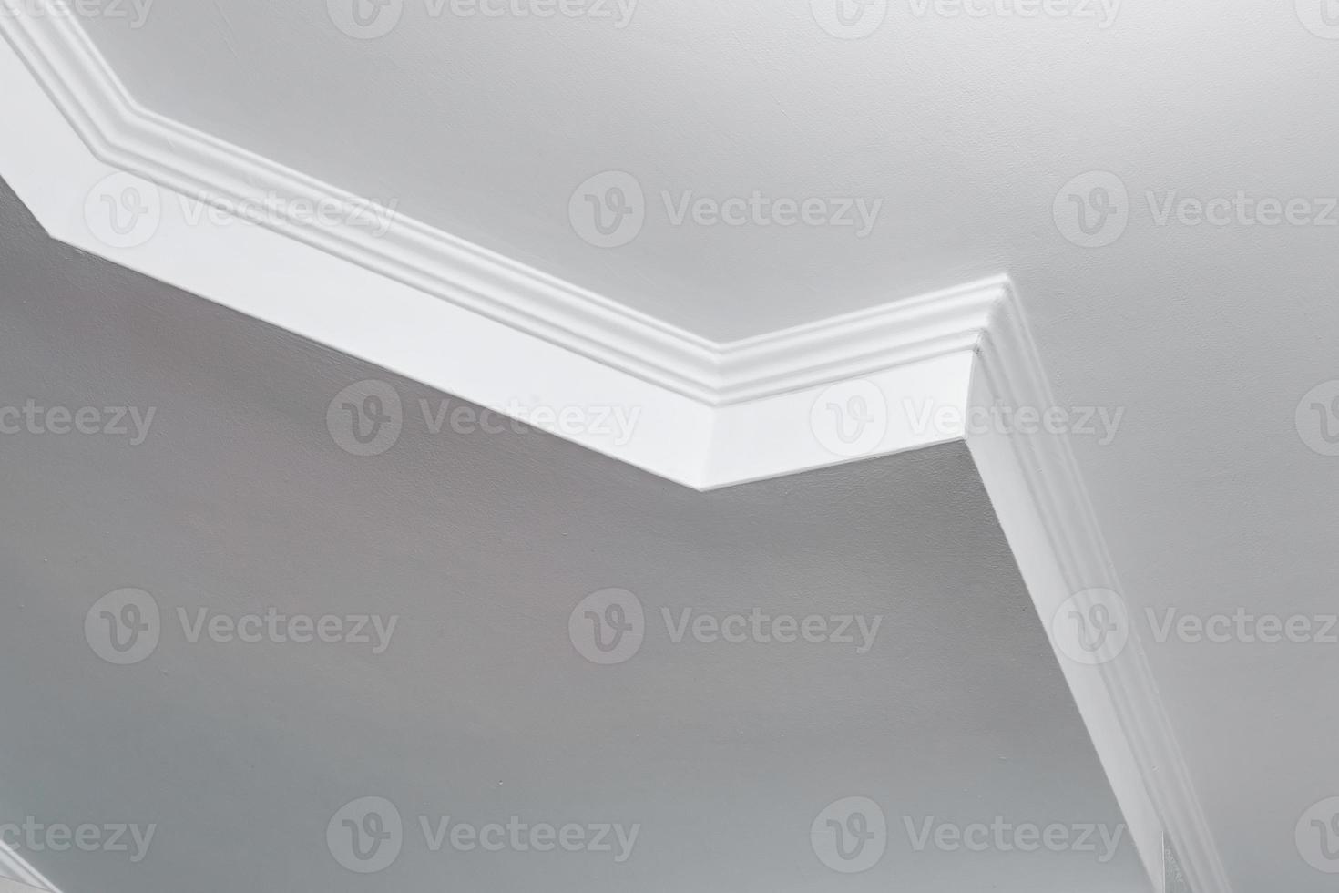 Detail of corner ceiling with intricate crown molding. Suspended ceiling and drywall construction in empty room in apartment or house. Stretch ceiling white and complex shape. photo