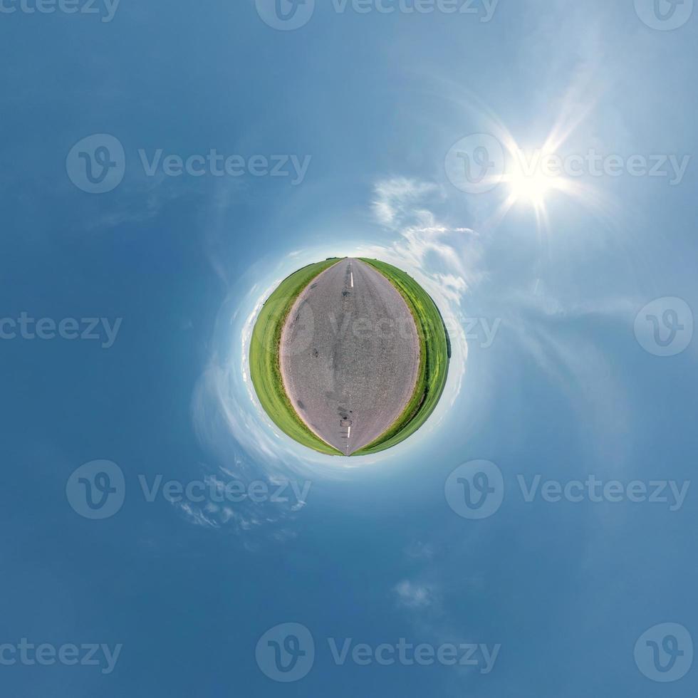 green tiny planet in blue sky with beautiful clouds. Transformation of spherical panorama 360 degrees. Spherical abstract aerial view. Curvature of space. photo