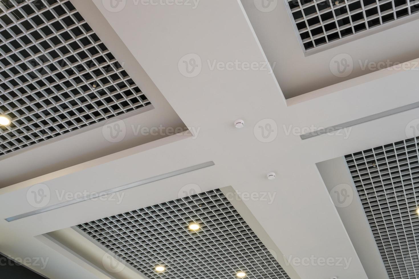 suspended and grid ceiling with halogen spots lamps and drywall construction in empty room in store or house. Stretch ceiling white and complex shape. photo