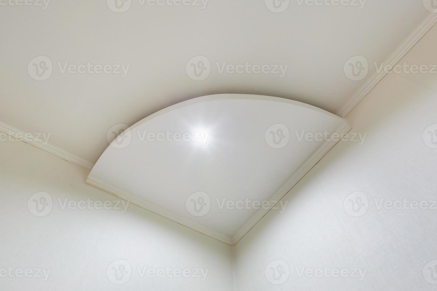 Detail of corner ceiling with intricate crown molding. Suspended ceiling and drywall construction in empty room in apartment or house. Stretch ceiling white and complex shape. photo