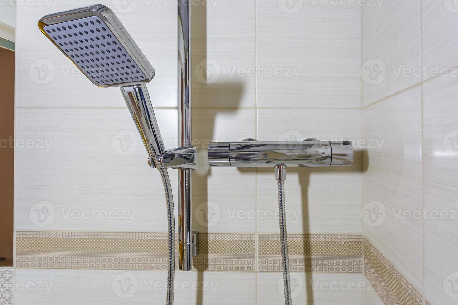 square water tap with faucet in expensive bathroom. detail of a corner shower cabin with wall mount shower attachment photo