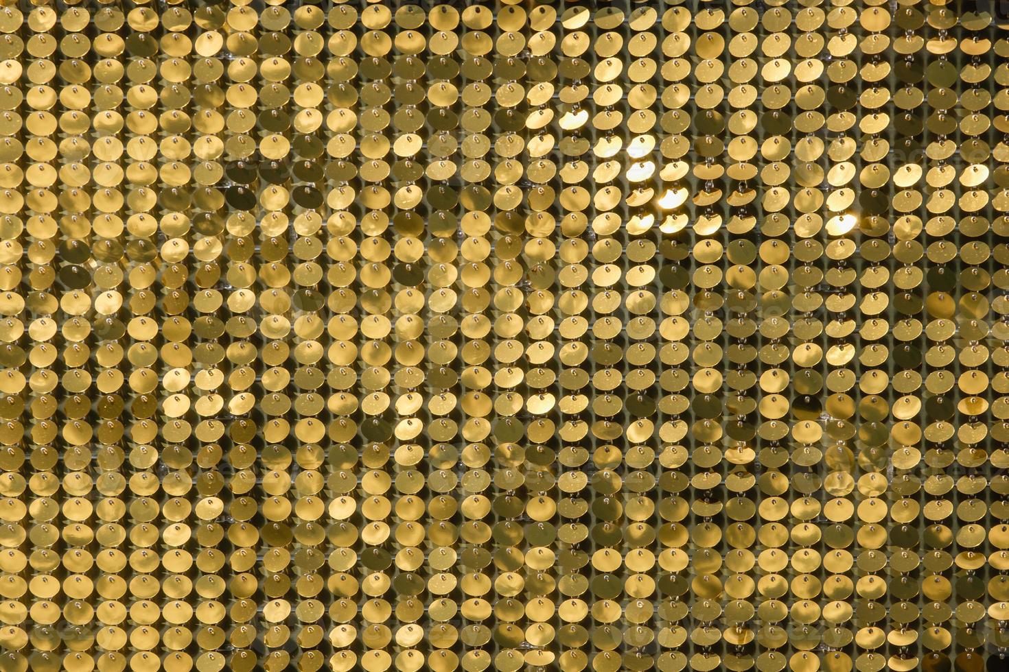 rows of blinking golden yellow brass metal plaques sway in wind and shines in sun and create unique pattern of movement. round reflective particles texture glitter under waves of wind. Spangle Glitter photo