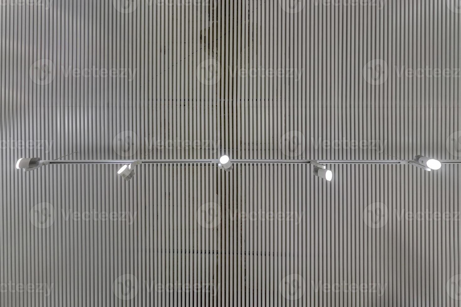 cassette suspended ceiling with square halogen spots lamps and drywall construction in empty room in apartment or house. Stretch ceiling white and complex shape. Looking up view photo