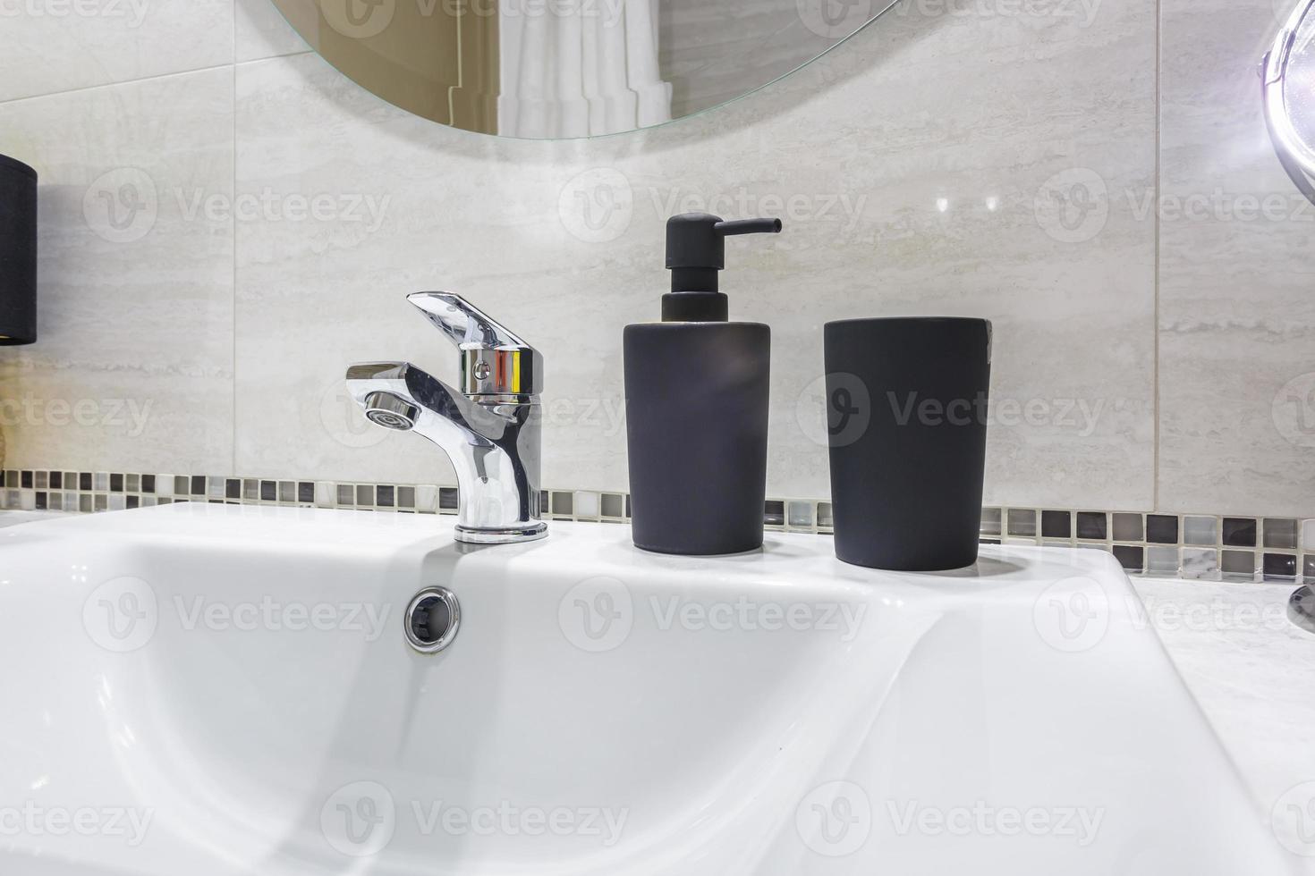 Ceramic Water tap sink with faucet with black soap and shampoo dispensers in expensive bathroom photo