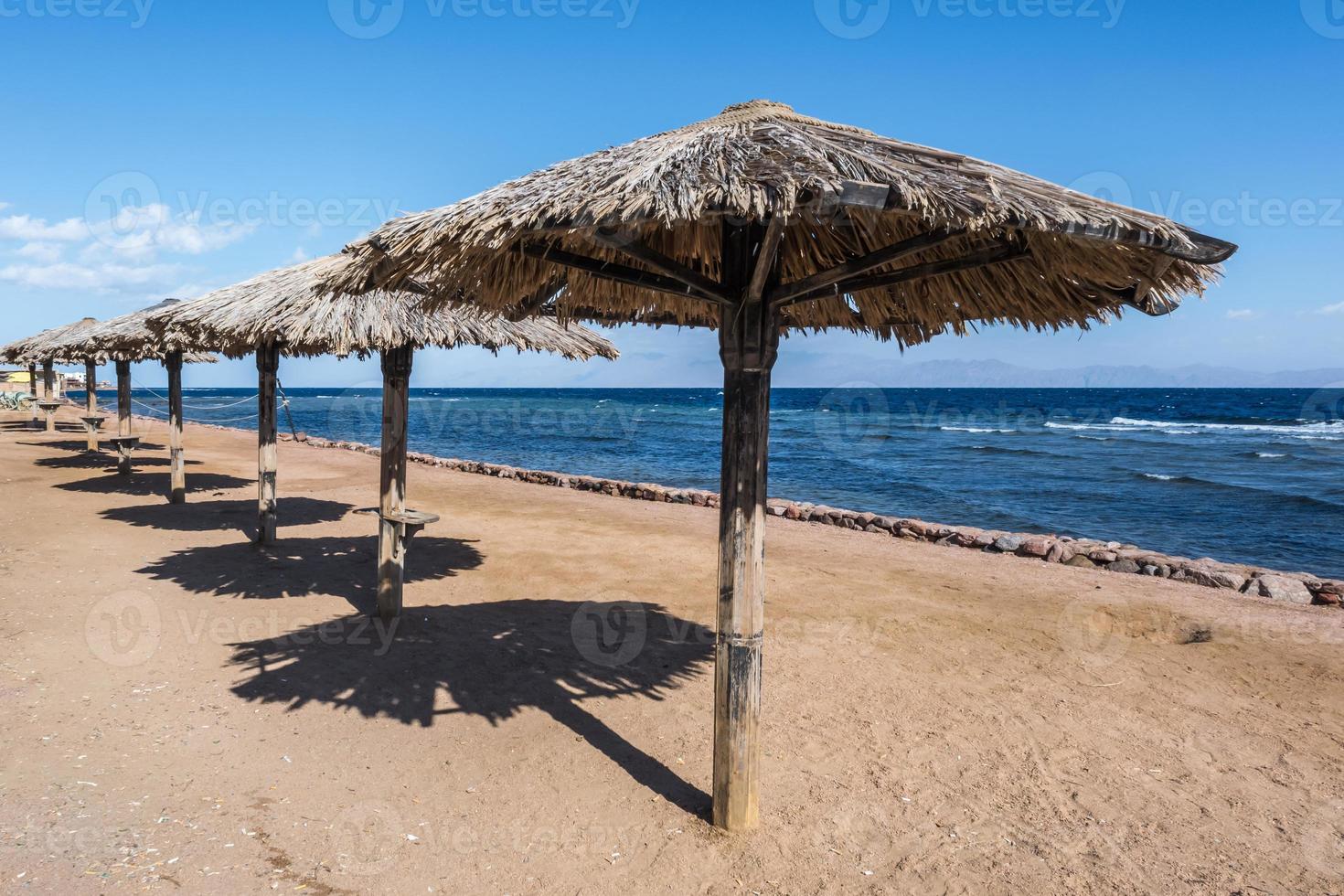 wooden beach umbrellas and sun loungers by the red sea in bright sunny day photo