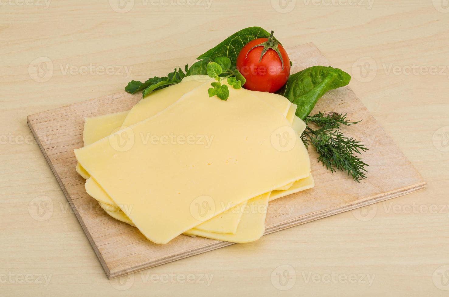 queso en lonchas sobre tabla de madera foto