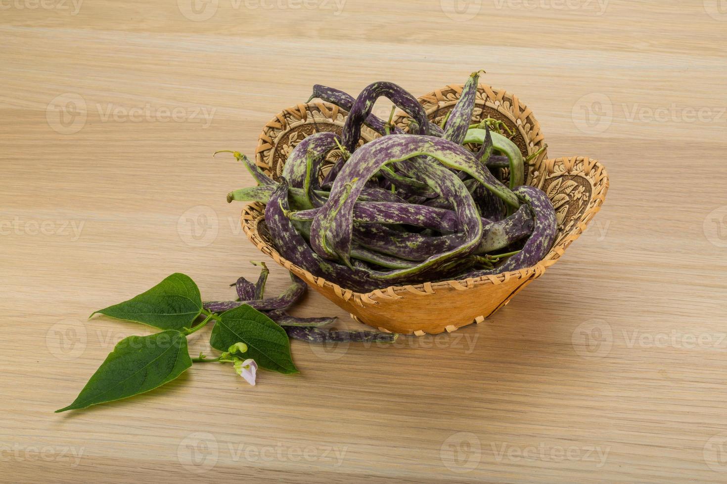 frijoles con hojas en una canasta sobre fondo de madera foto