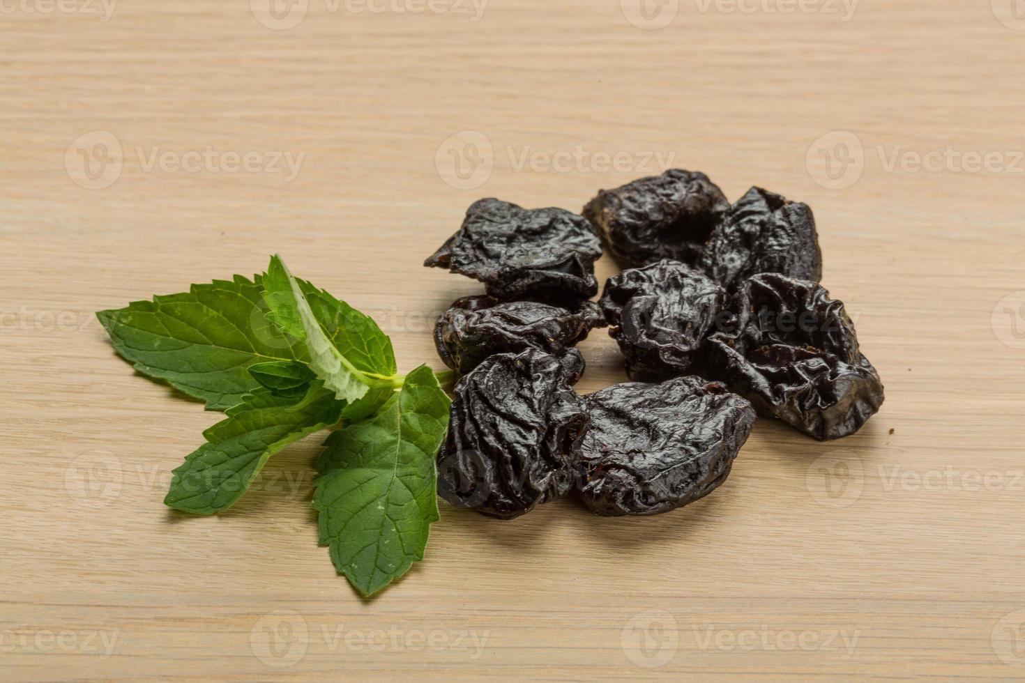 Dry plums on wooden background photo