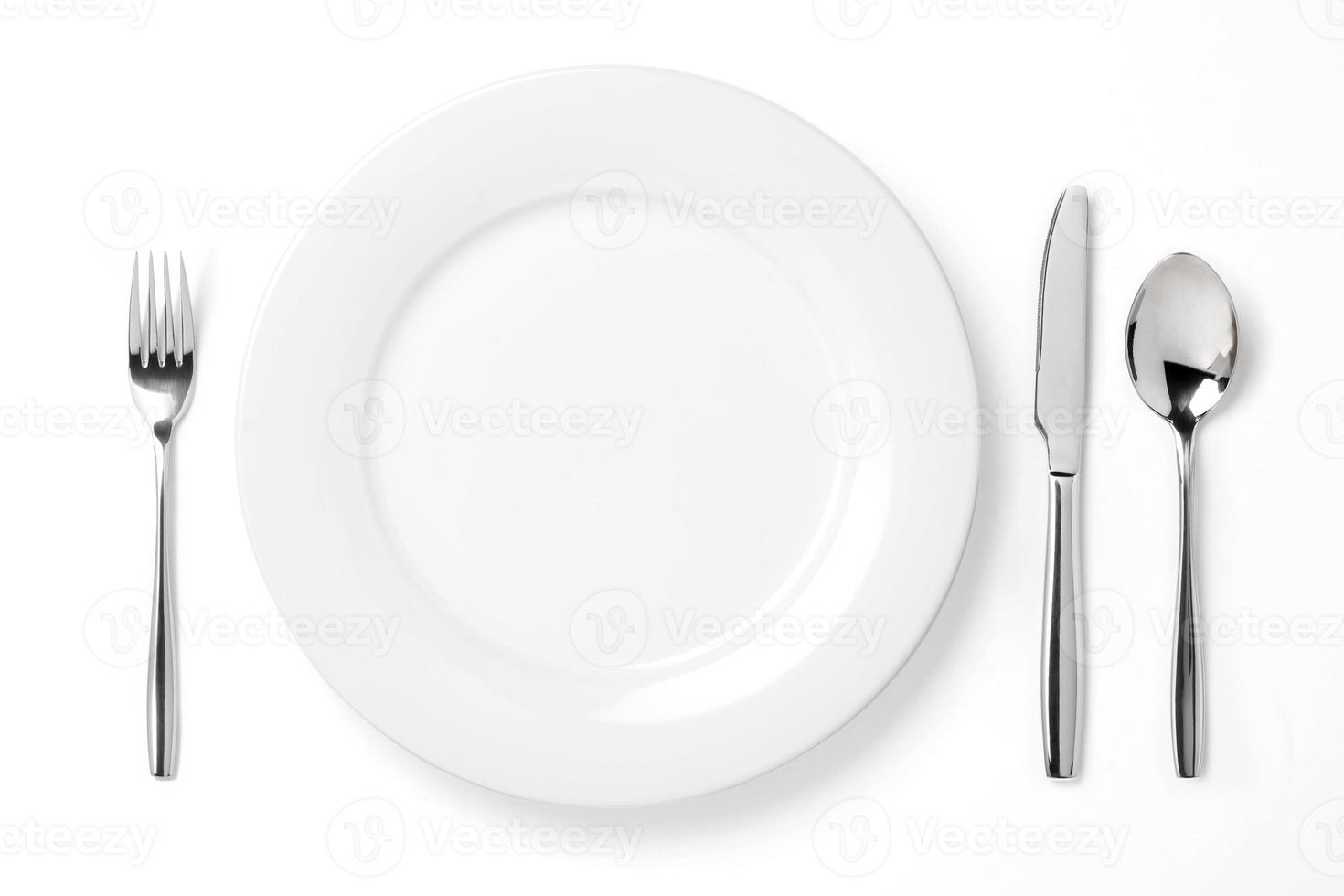 plato vacío con cuchara, cuchillo y tenedor aislado en un blanco foto