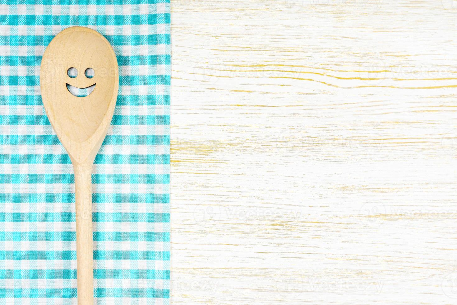 Kitchen mockup. Wooden spoon with smile on white wooden background. Food background with copy space photo