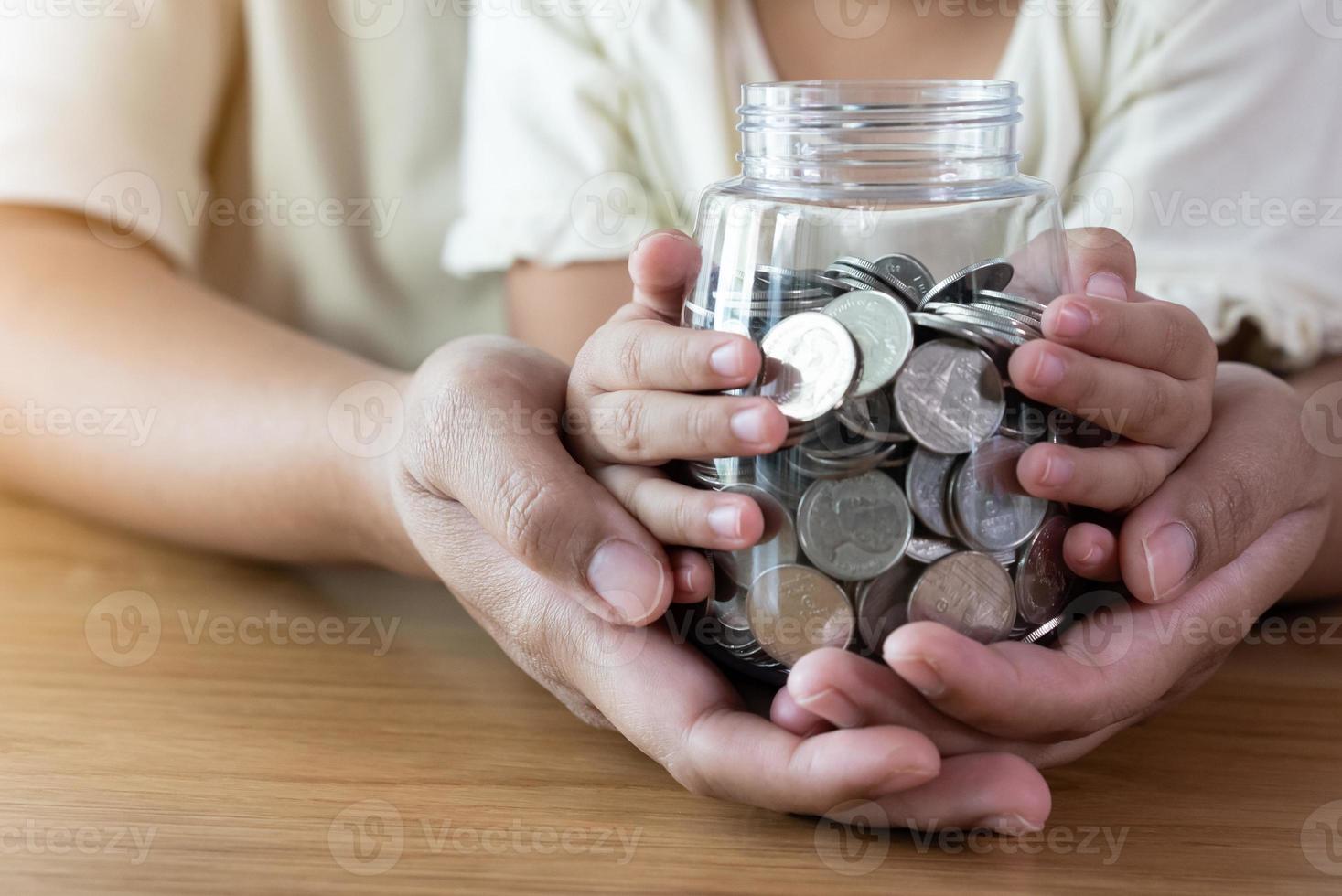 Adult and kid hands holding a coins jar savings and donation concept photo