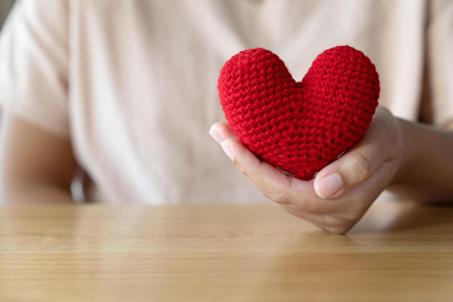 Adult hand holding a yarn red heart photo