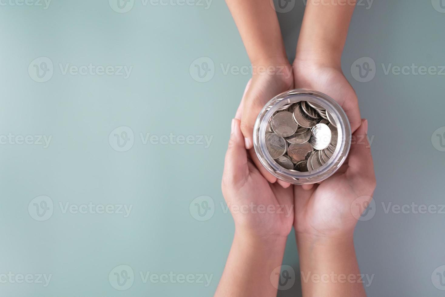 manos de adultos y niños sosteniendo un frasco de monedas concepto de ahorro y donación foto