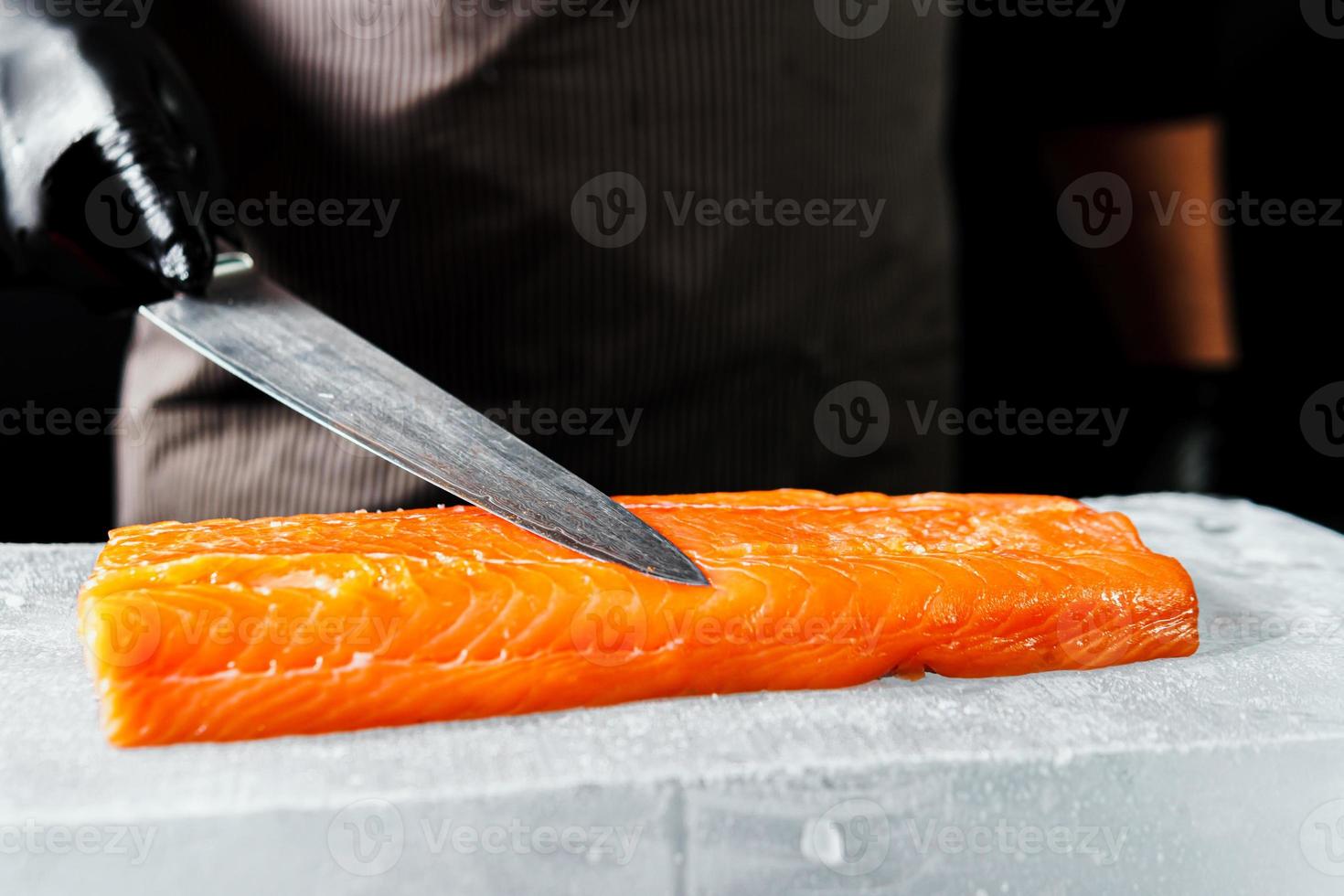 Close-up of chef hand prepared to cooking fresh salmon fillet, black background photo