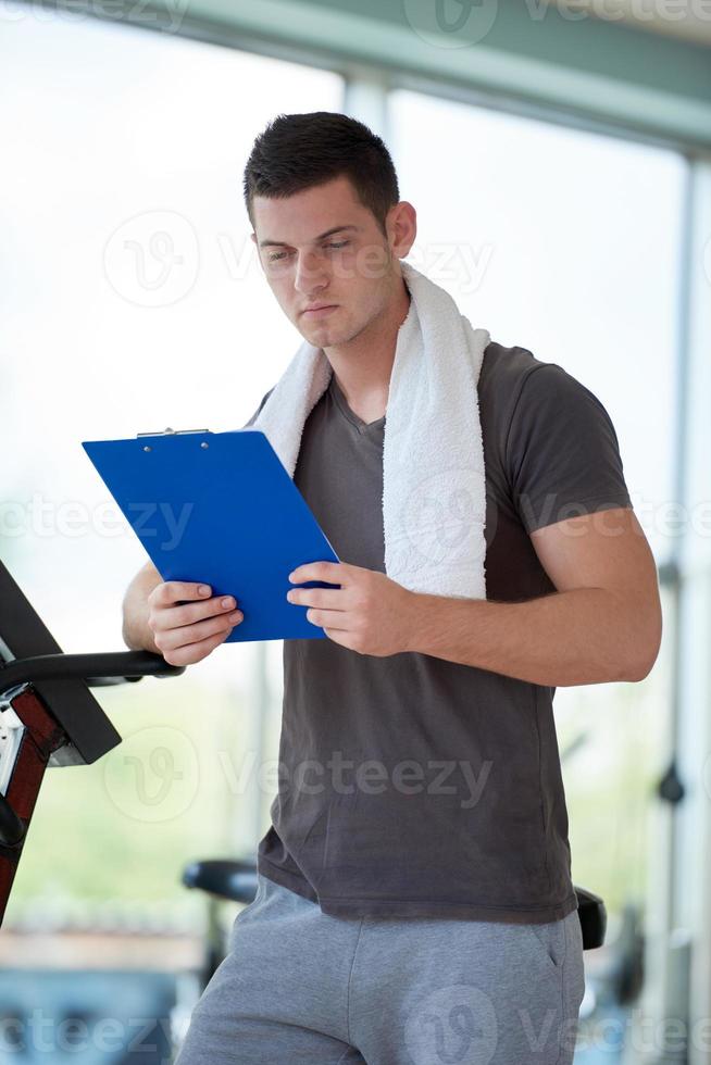 trainer with clipboard standing in a bright gym photo