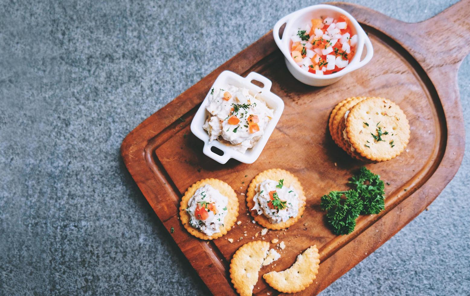 Top view of tasty tuna spread with crackers on wooden tray, copy space photo