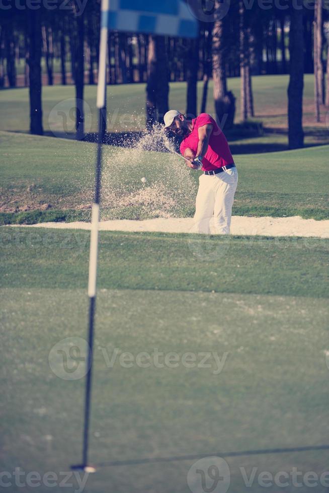 golfer hitting a sand bunker shot photo