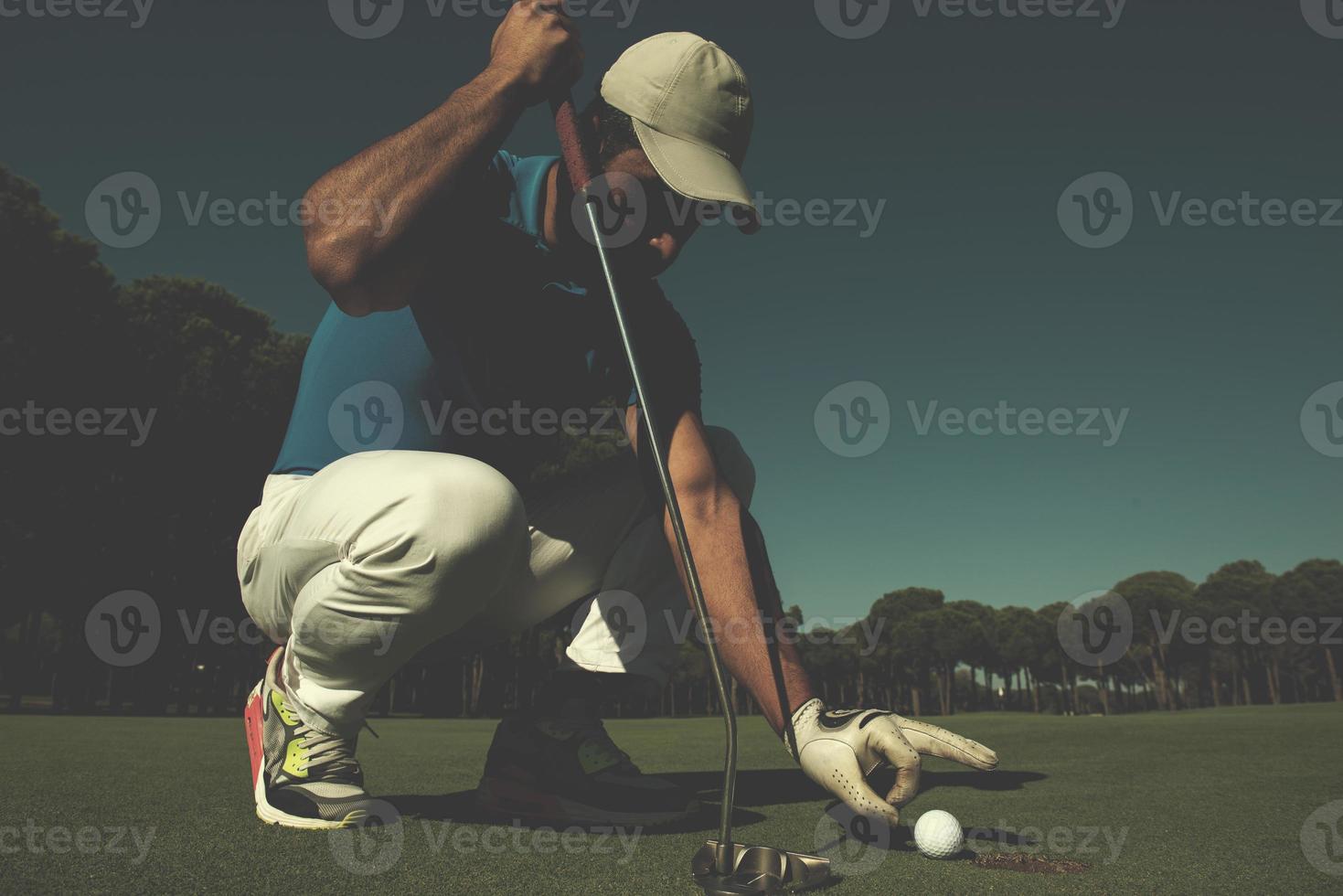 man's hand putting golf ball in hole photo