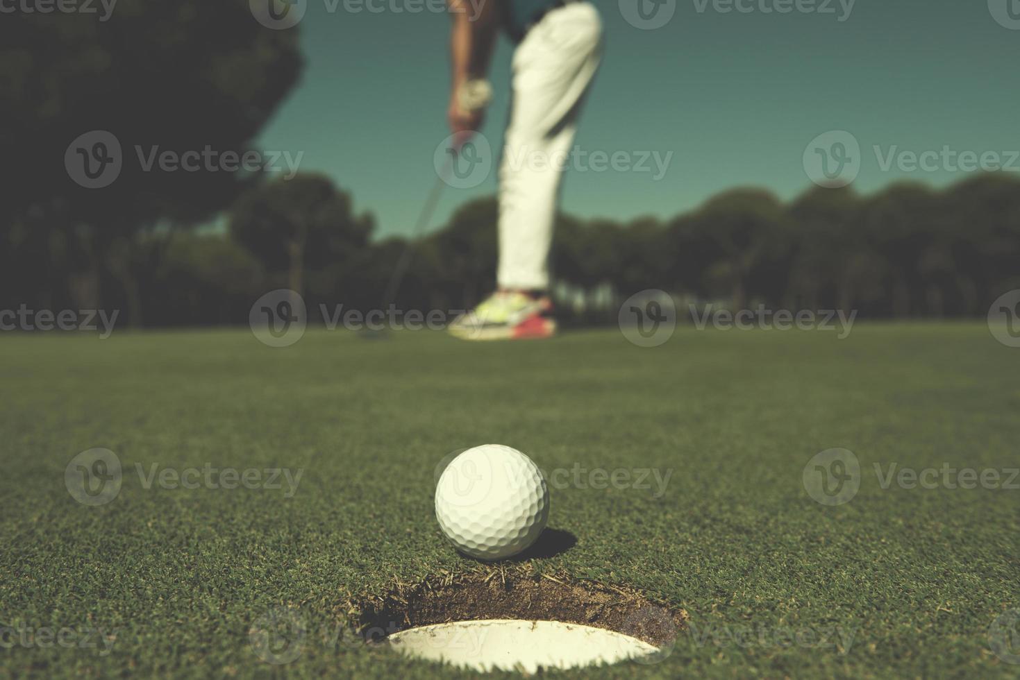 jugador de golf golpeando tiro, bola en el borde del hoyo foto