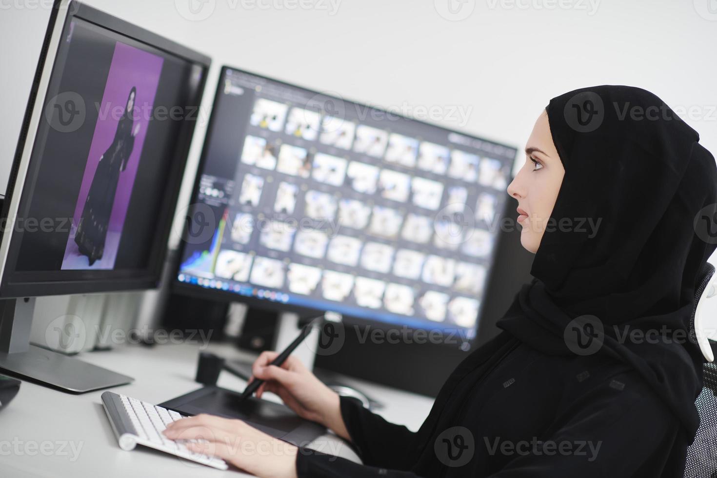 Muslim female graphic designer working on computer using graphic tablet and two monitors photo