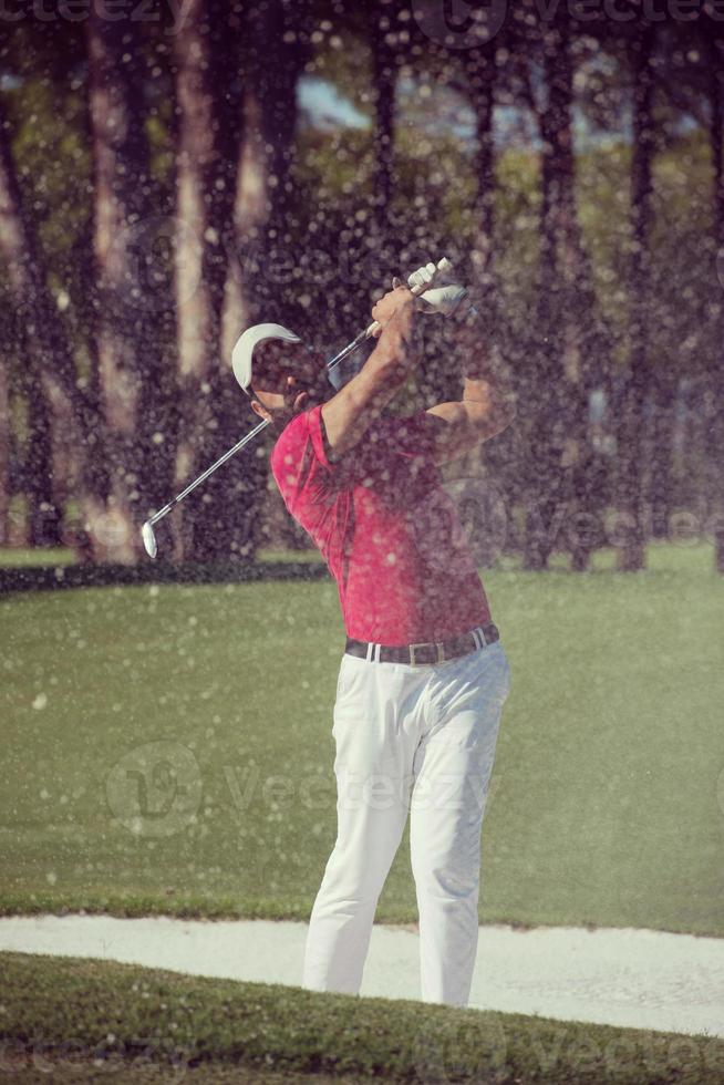 golfer hitting a sand bunker shot photo