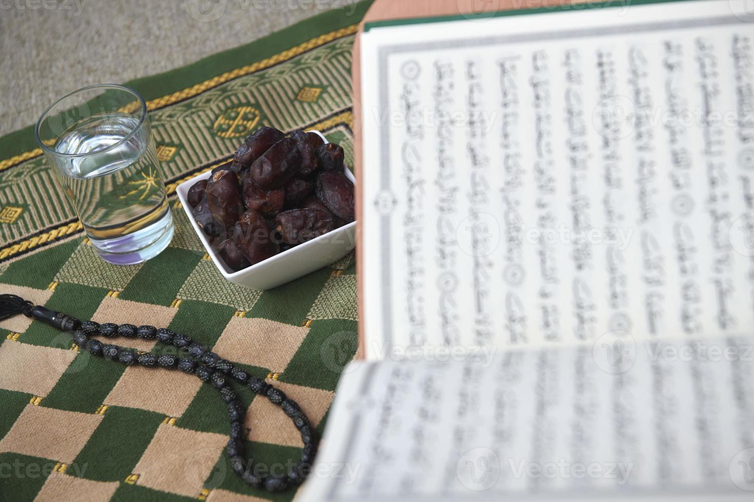 Iftar time dried dates holy Quran  glass of water and tasbih on praying  rug or sejadah photo